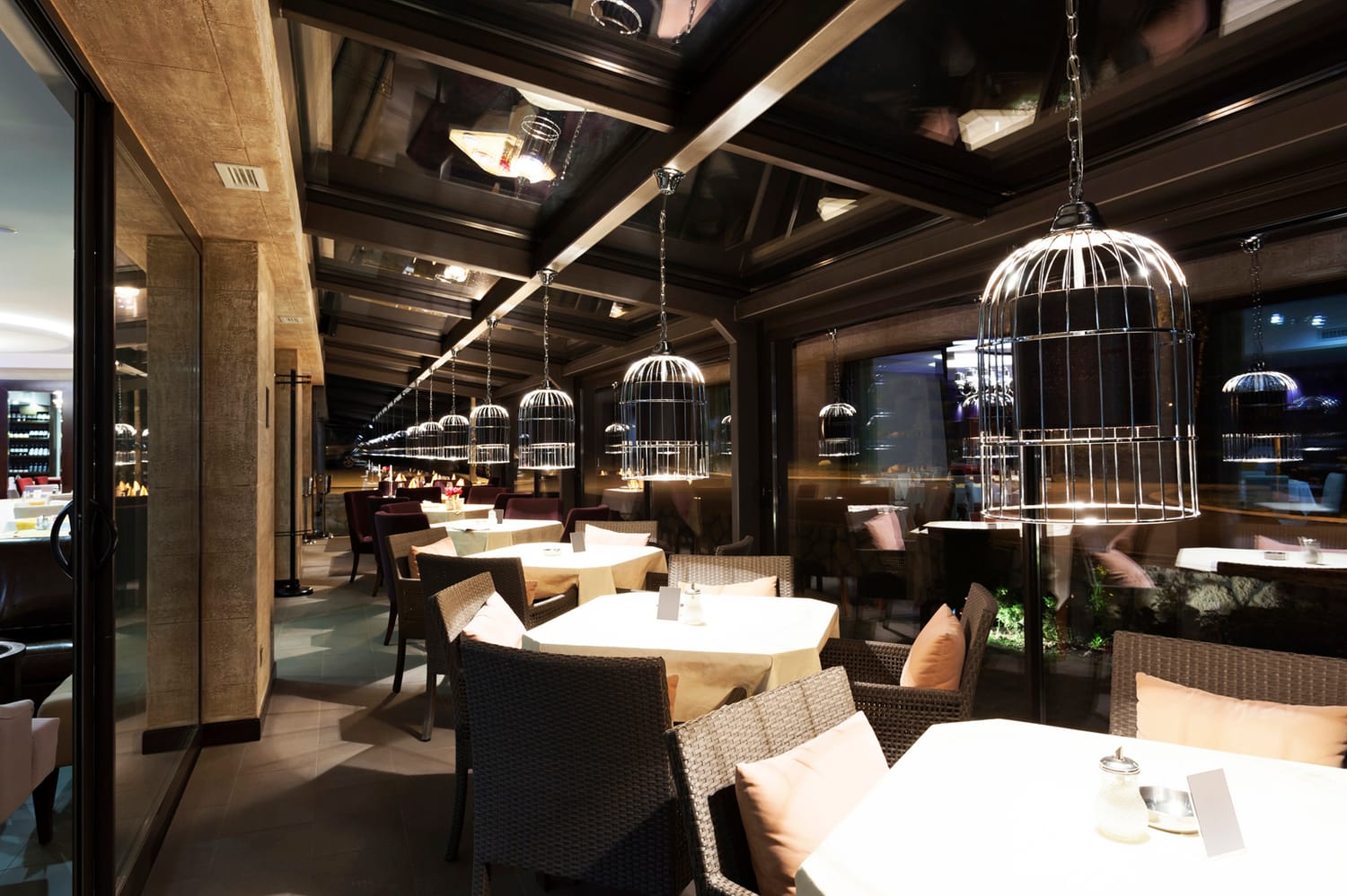 The Shamora dining room at night, warm light and birdcage pendant lamps over set tables